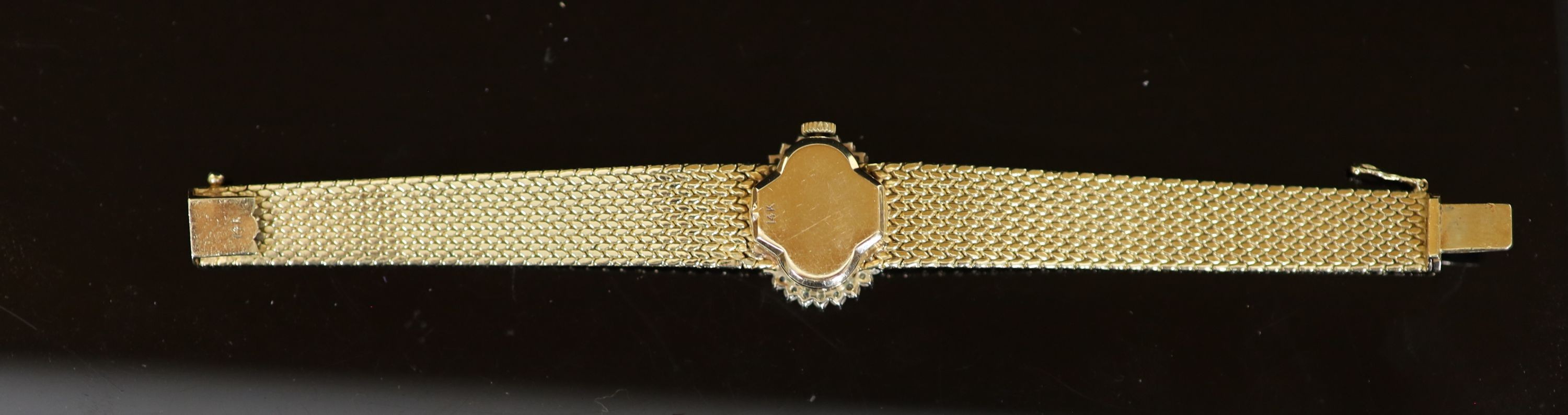 A lady's modern Swiss 14k gold and diamond set manual wind oval wrist watch, on integral 14k gold bracelet